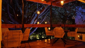 An outdoor seating area with wicker chairs and tables, wooden beams, and hanging lanterns. - La Provence Restaurant & Boutique Hotel (Cuernavaca)