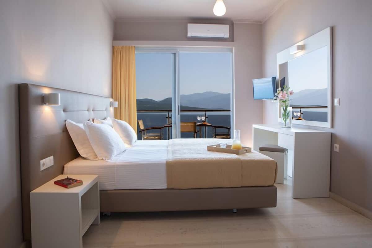 Habitació d'hotel moderna amb un llit gran, escriptori, televisió i un balcó amb vista a les muntanyes.