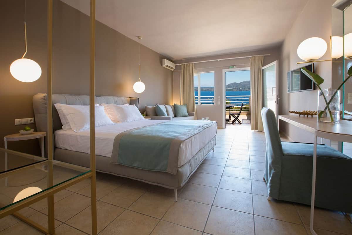Una habitació d'hotel moderna amb un llit gran, un escriptori i vista al mar.
