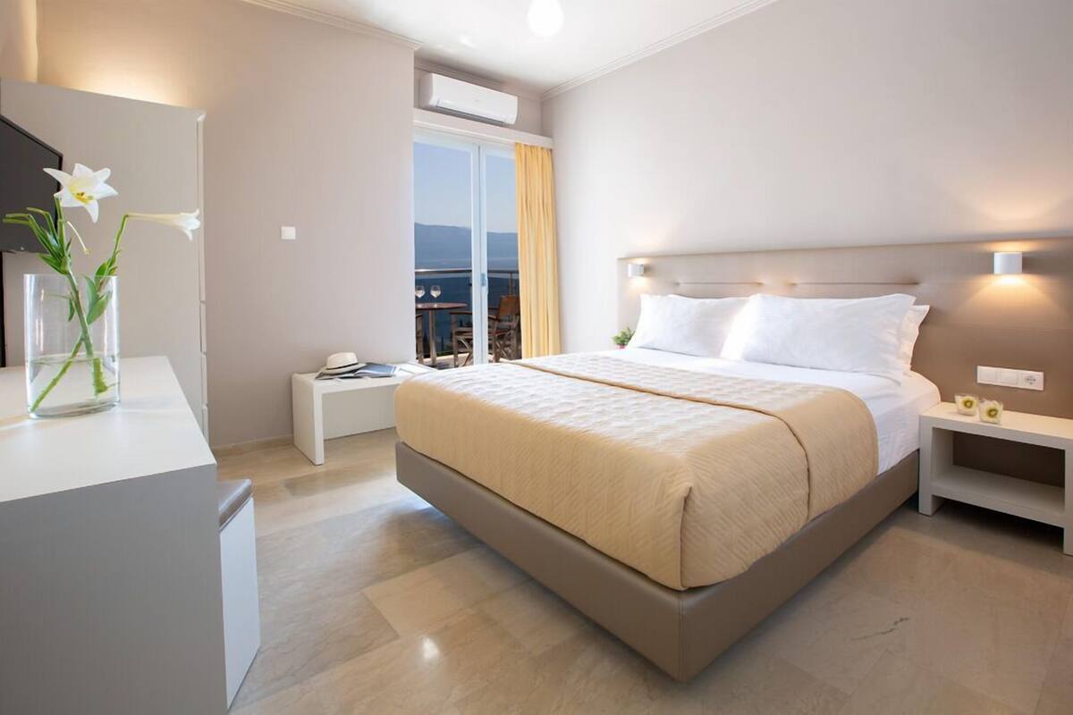 Habitació d'hotel moderna amb un llit gran, una taula de nit, un mirall i vista al mar.