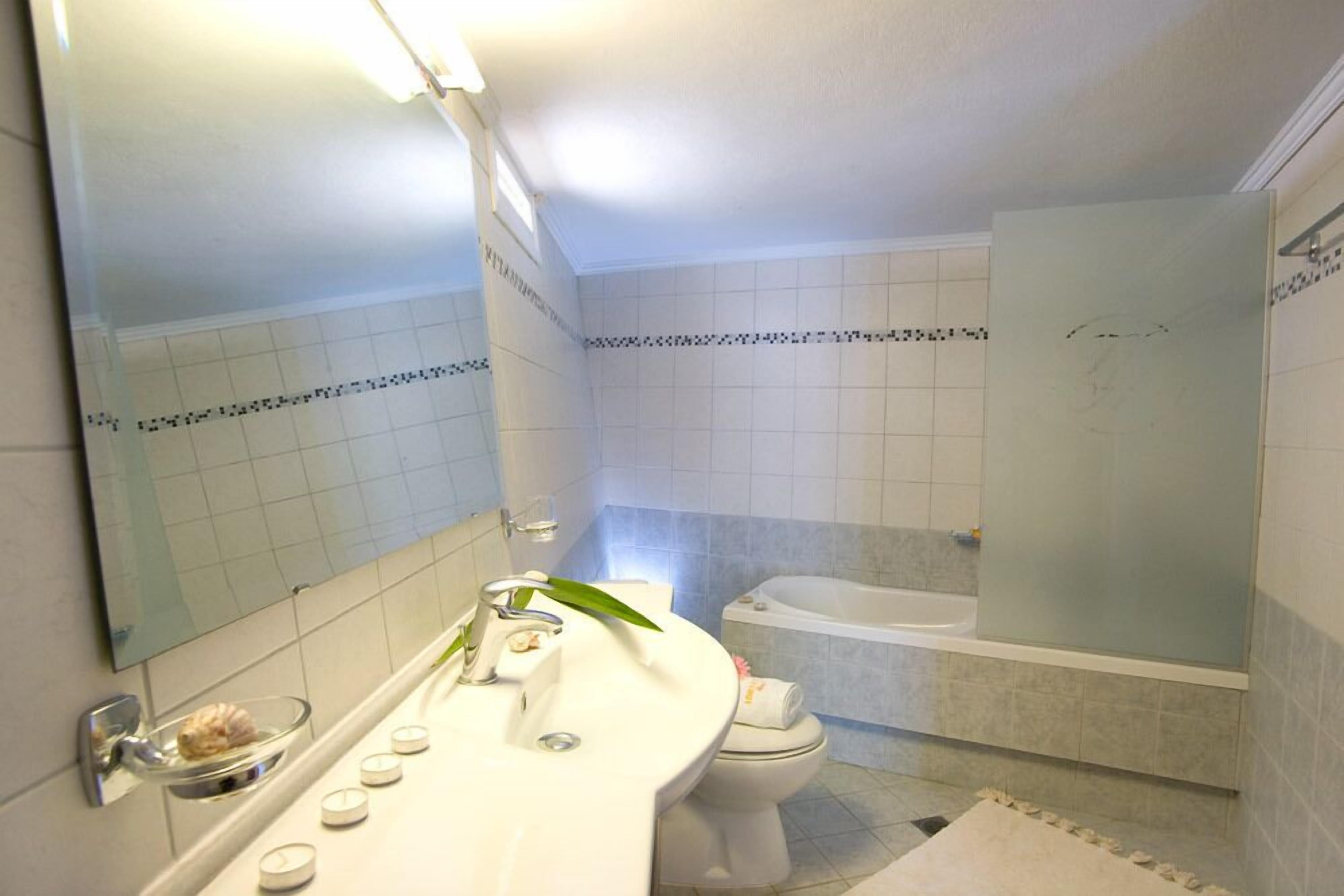 A bathroom with a white sink, mirror, and a bathtub.