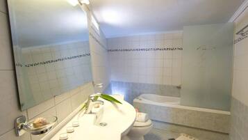 A bathroom with a white sink, mirror, and a bathtub.