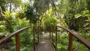 A wooden bridge with metal railings in a lush, green garden setting. - Embudu Village (Emboodhoo)