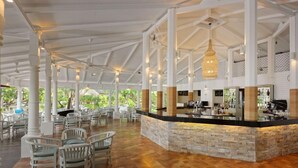 A spacious outdoor lounge area with a stone bar and white chairs. - Embudu Village (Emboodhoo)