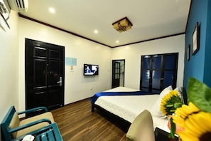 A hotel room with a bed, a TV, a desk, and a chair.