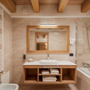 A bathroom with a wooden vanity, a large mirror, a white sink, and a shower area.