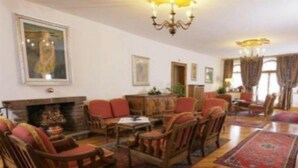 A traditional living room with a fireplace, wooden furniture, and patterned rugs. - Royal Hotel Cortina (Cortina d'Ampezzo)