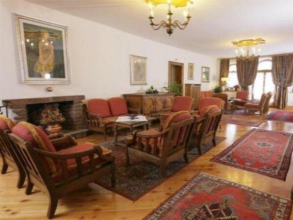 A traditional living room with a fireplace, wooden furniture, and patterned rugs. - Royal Hotel Cortina (Cortina d'Ampezzo)