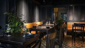 A restaurant with a long table, chairs, and potted plants.