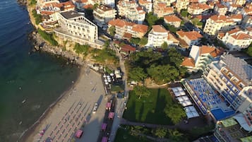 Eine Vogelperspektive einer Küstenstadt mit Strand, einem großen Gebäude mit weißer Fassade und einem dicht bebauten Wohngebiet.