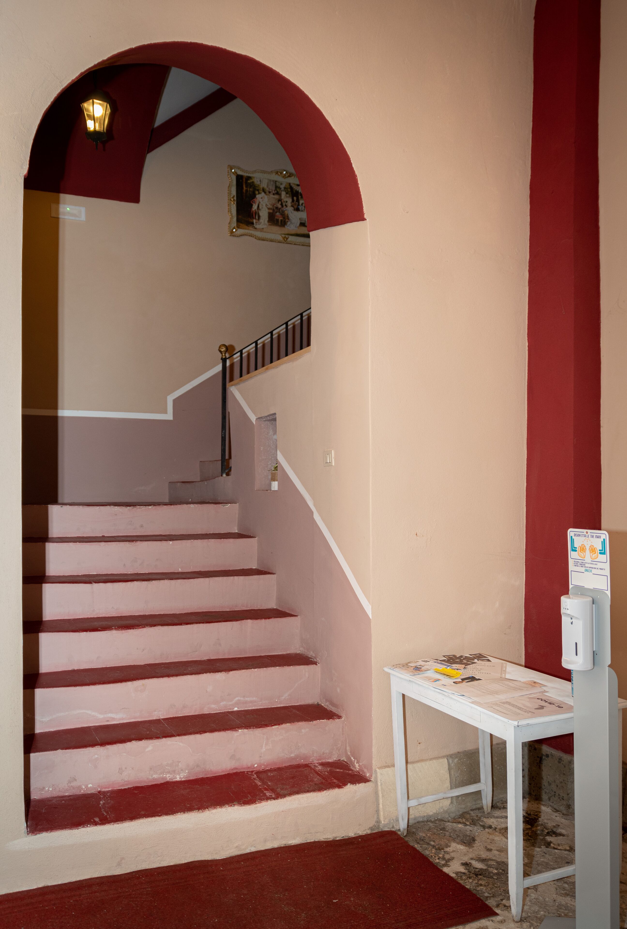 A staircase with a red handrail and a white table with a sign next to it.