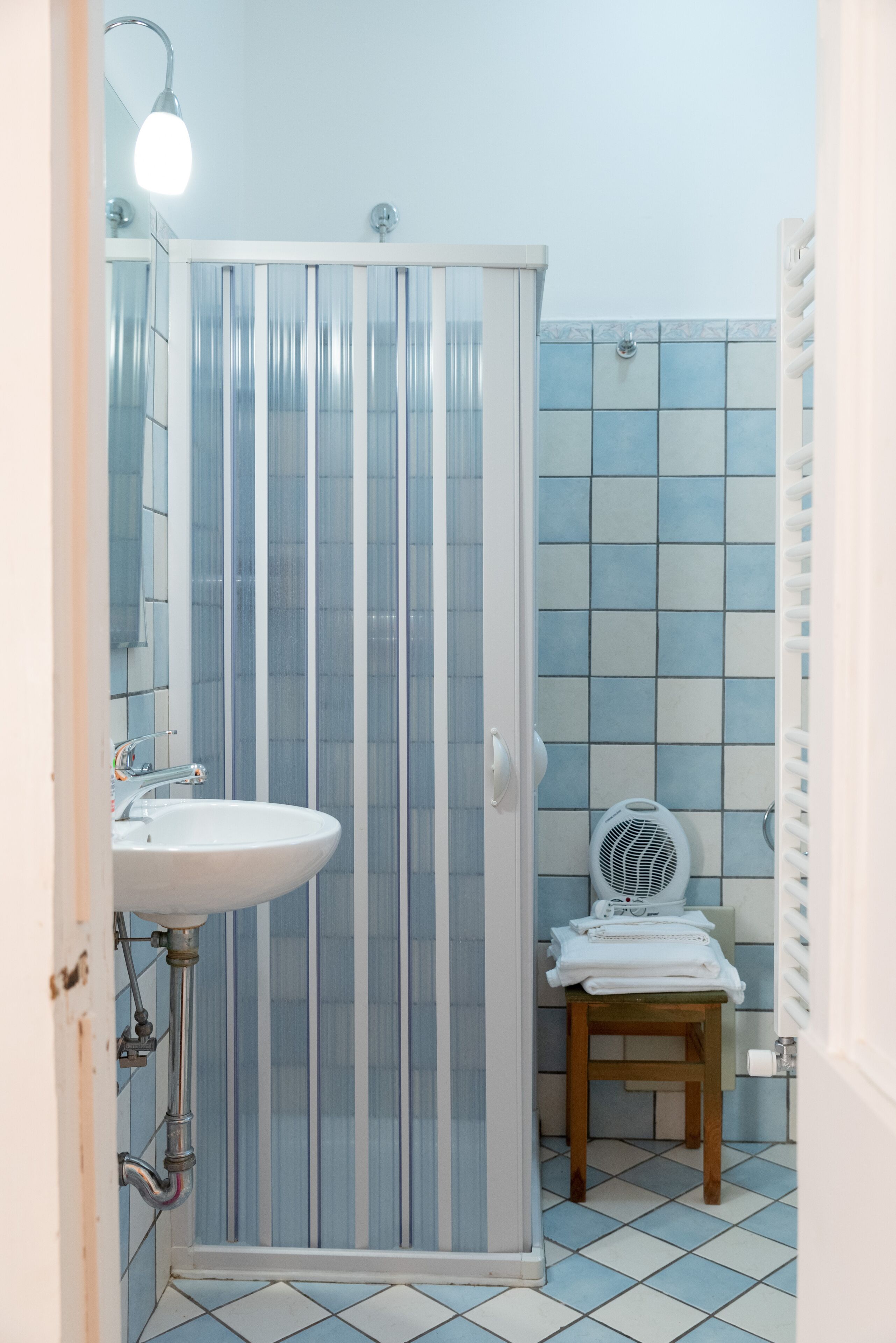 Un bagno con cabina doccia, lavandino, water e una sedia.