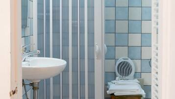 Un bagno con cabina doccia, lavandino, water e una sedia.