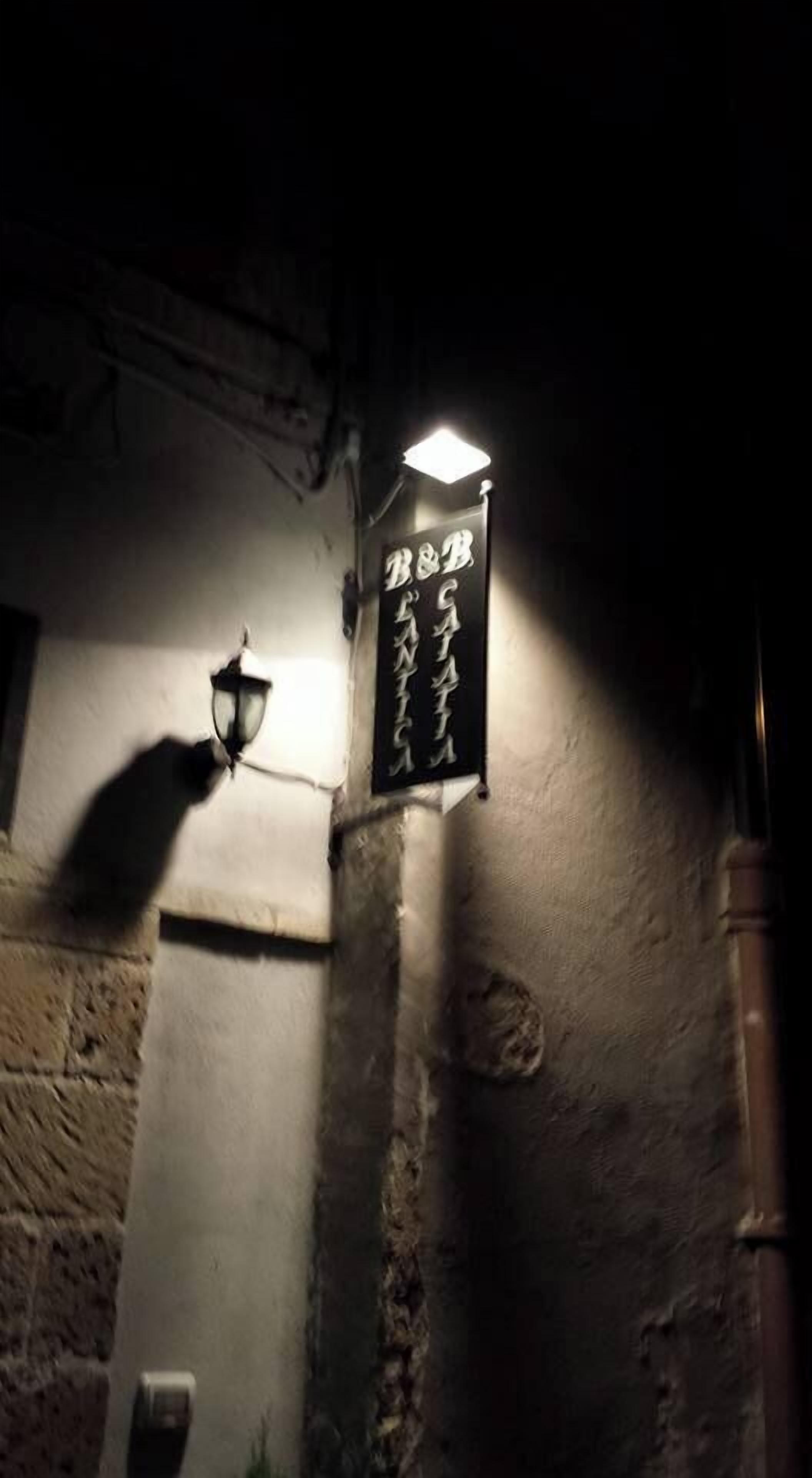 A sign with Japanese characters, a wall-mounted light fixture, and a stone wall.