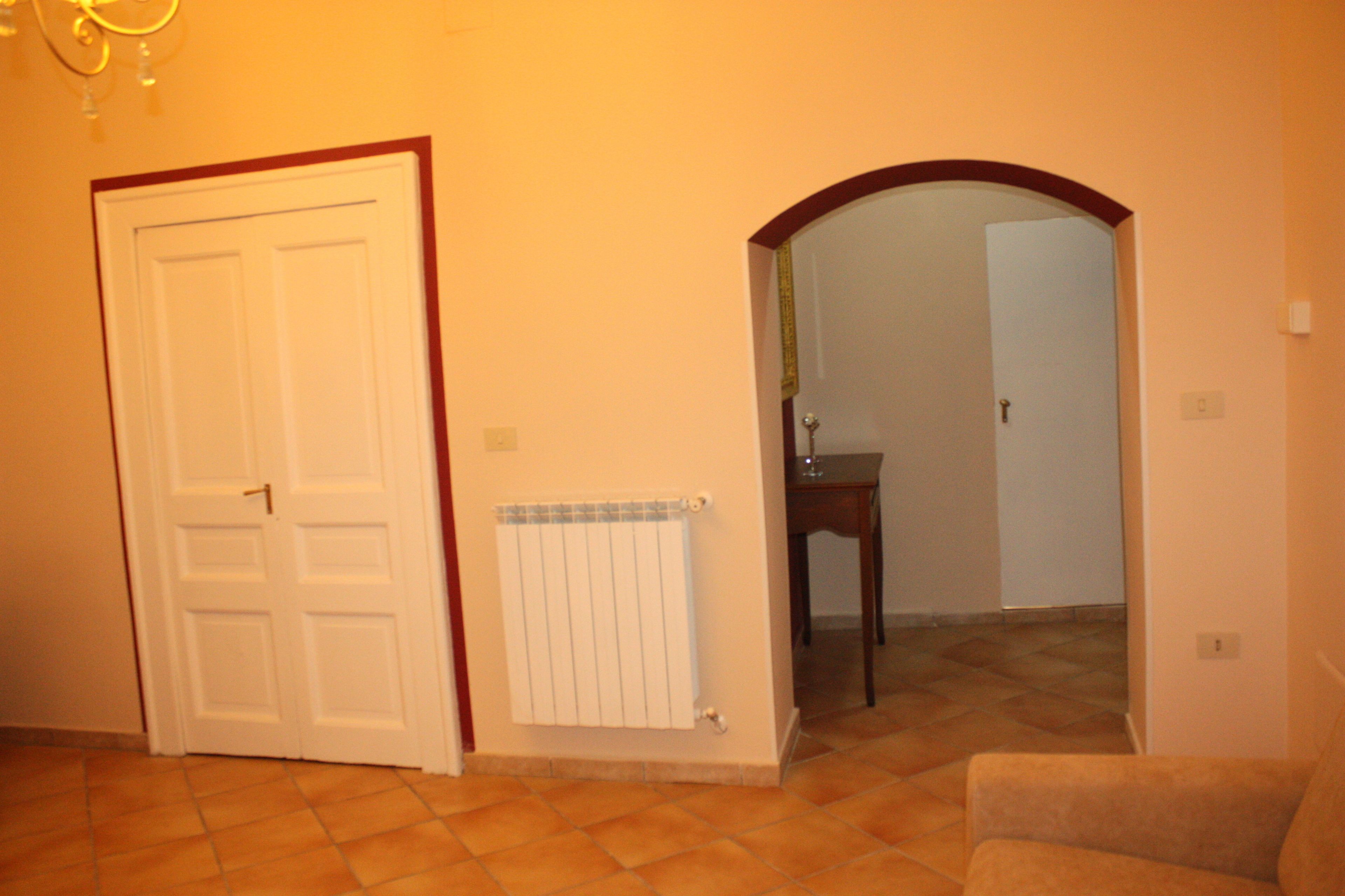 Una habitación con la puerta cerrada, un radiador, una mesita y una silla.