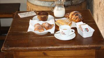 A wooden table with pastries, a coffee cup, and a milk jug.