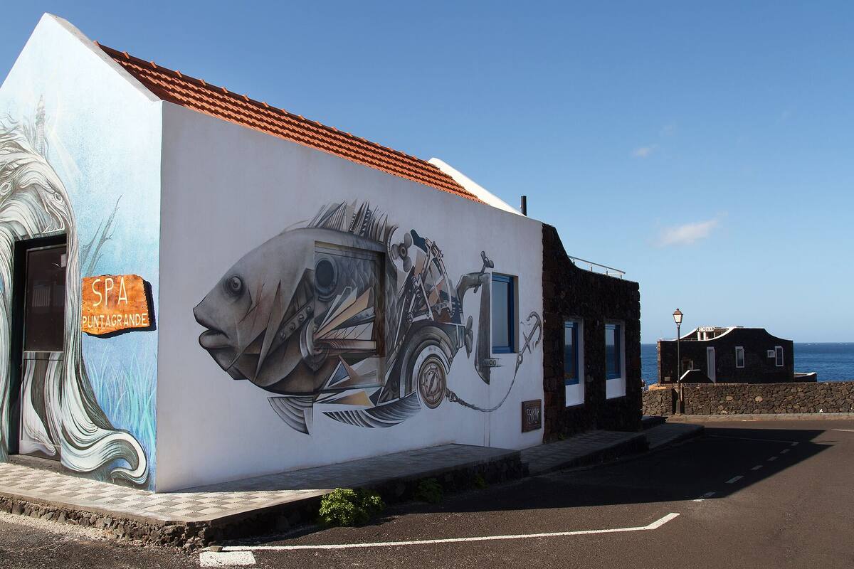 A building with a mural of a fish and a vintage bicycle.