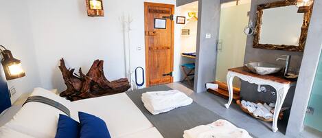 A modern bedroom with a bed, bedside table, and a bathroom with a sink and mirror.
