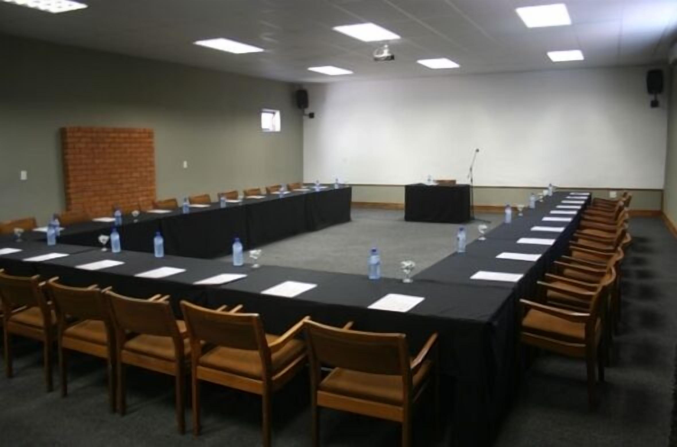 A conference room with a long table, chairs, and a podium.
