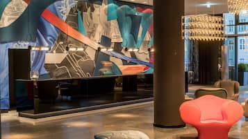 A modern lobby with a large abstract mural, contemporary seating, and a chandelier.
