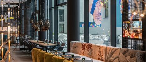 Un interior de restaurante moderno con una larga mesa de comedor, sillas amarillas y un sofá.