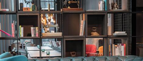 Una sala moderna con un sofá gris, un reposapiés amarillo y un jarrón rojo.