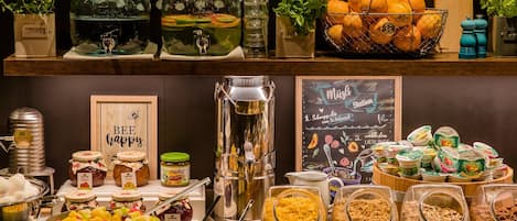 Un bufé con diversas opciones de comida, incluyendo ensalada de frutas, copos de maíz y granola.