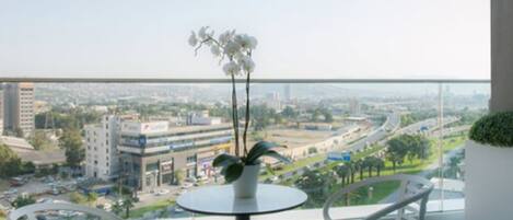 Un balcón con una mesa redonda y dos sillas, con vistas a un paisaje urbano de edificios y calles.