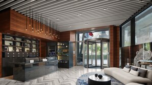 A modern lobby with a reception desk, a seating area, and a view of the outside.