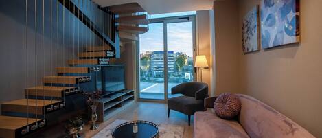 A modern living room with a staircase, a sofa, a coffee table, and a TV.