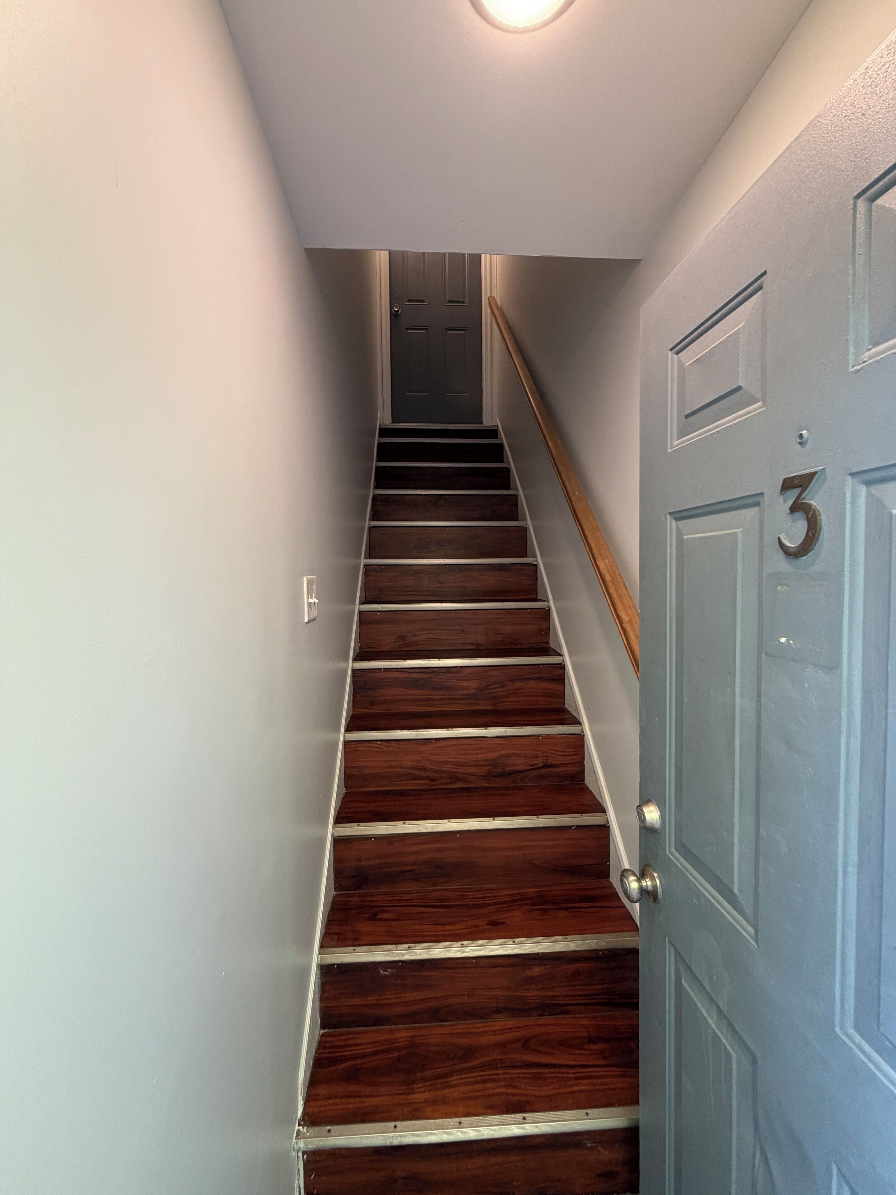Una escalera de madera con peldaños que lleva a una puerta con el número 3.