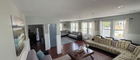 A spacious living area with a sofa, a coffee table, and a patterned sofa set.