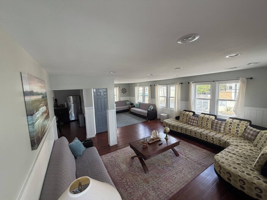 A spacious living area with a sofa, a coffee table, and a patterned sofa set.