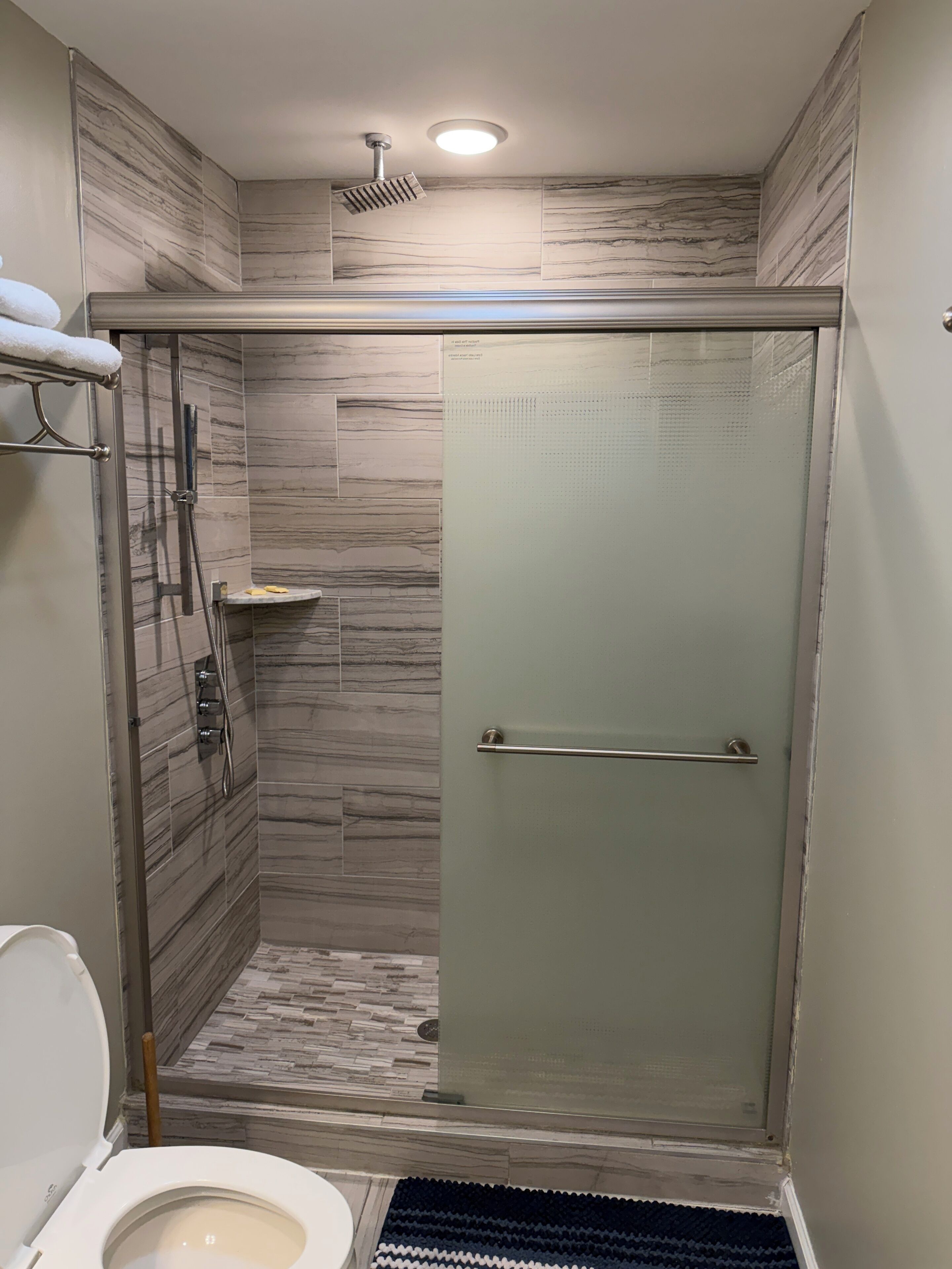 Un baño moderno con ducha acristalada, inodoro y perchero para toallas.