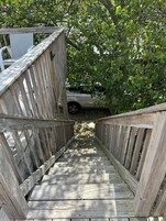 Una escalera de madera que lleva a un espacio cubierto con un vehículo estacionado cerca.