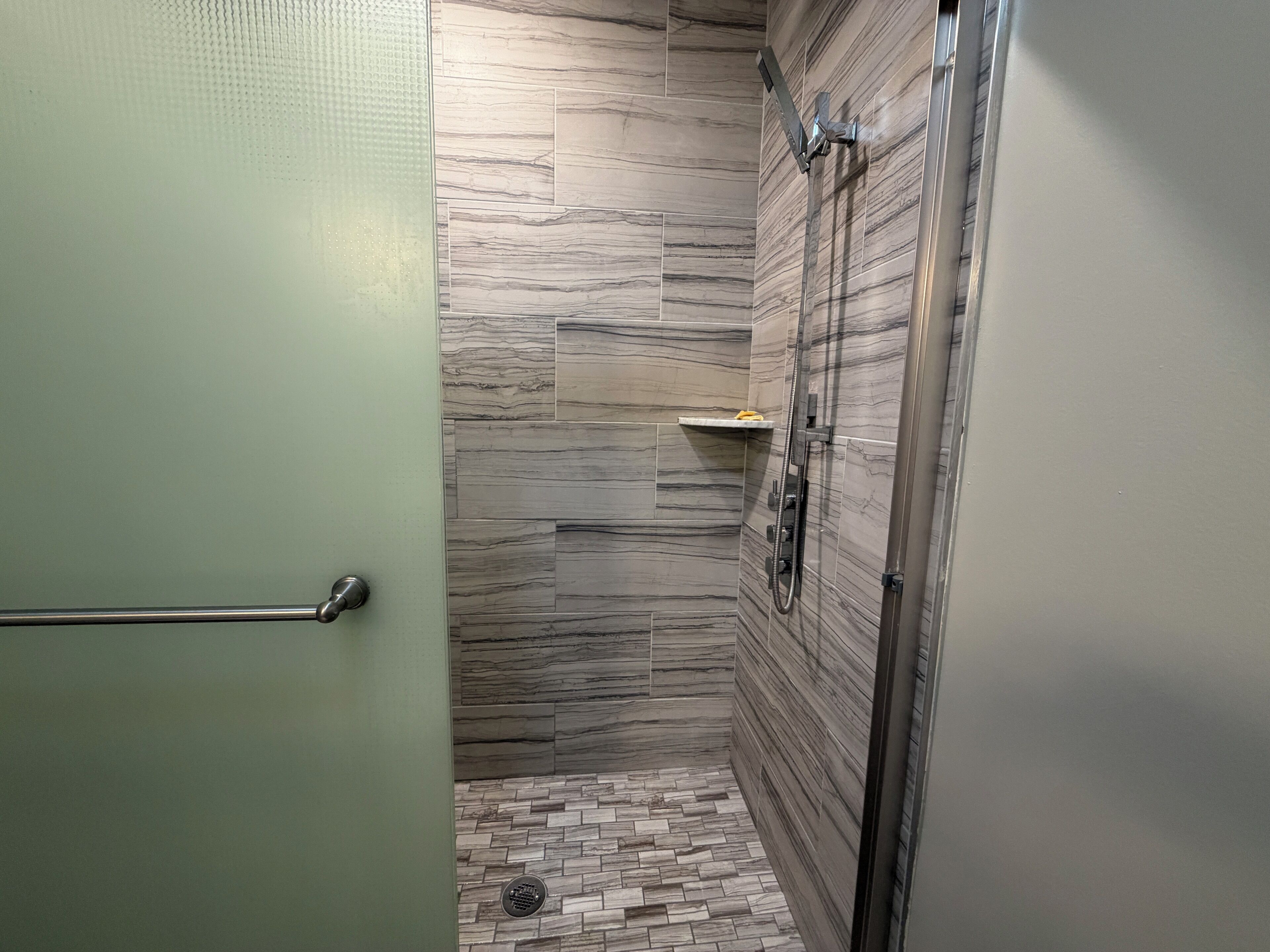A modern bathroom with a shower, tiled walls, and a green door.