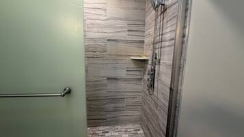 A modern bathroom with a shower, tiled walls, and a green door.