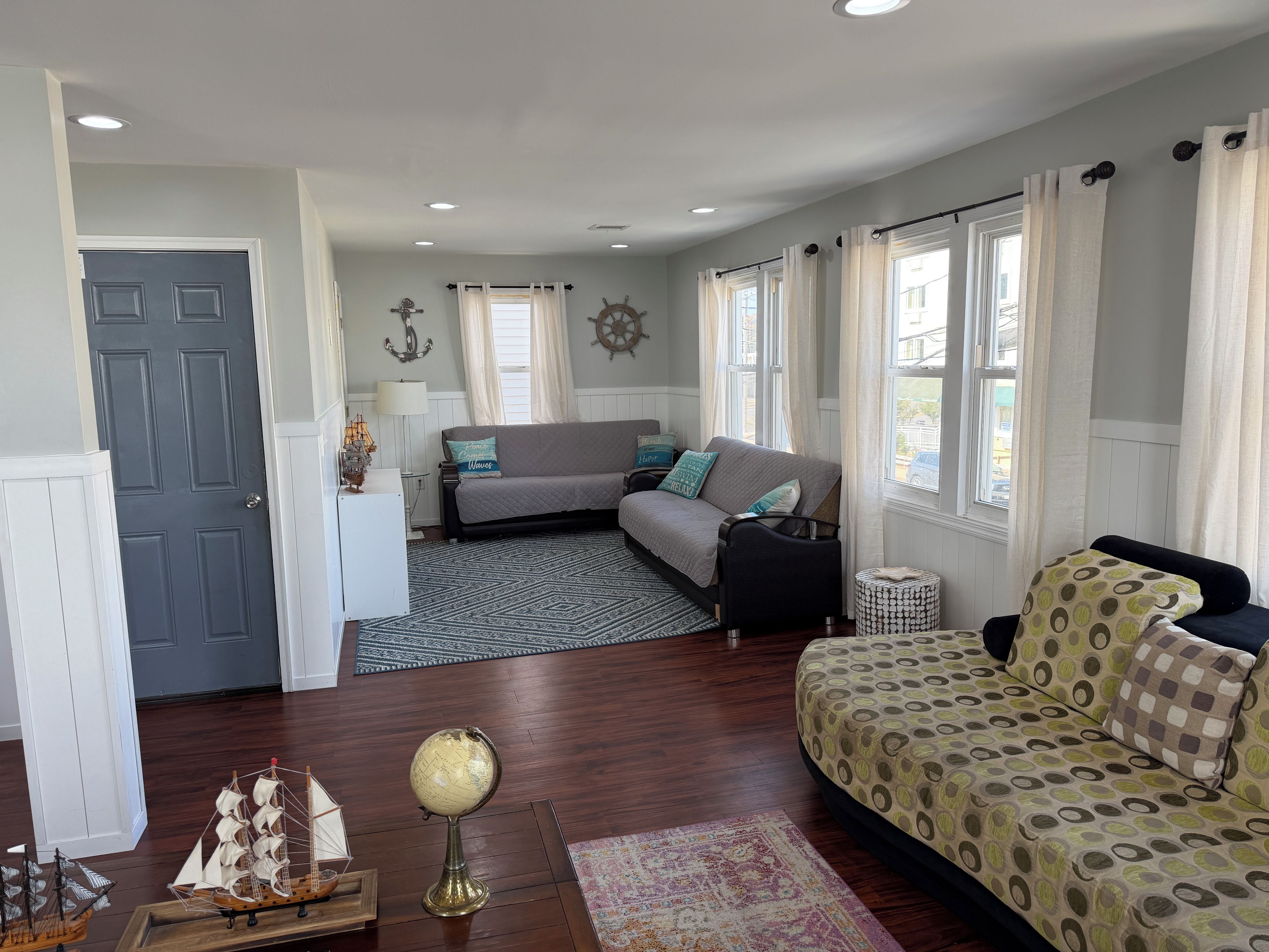 A cozy living room with a sofa, a patterned armchair, a globe, and a ship model.
