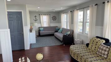 A cozy living room with a sofa, a patterned armchair, a globe, and a ship model.