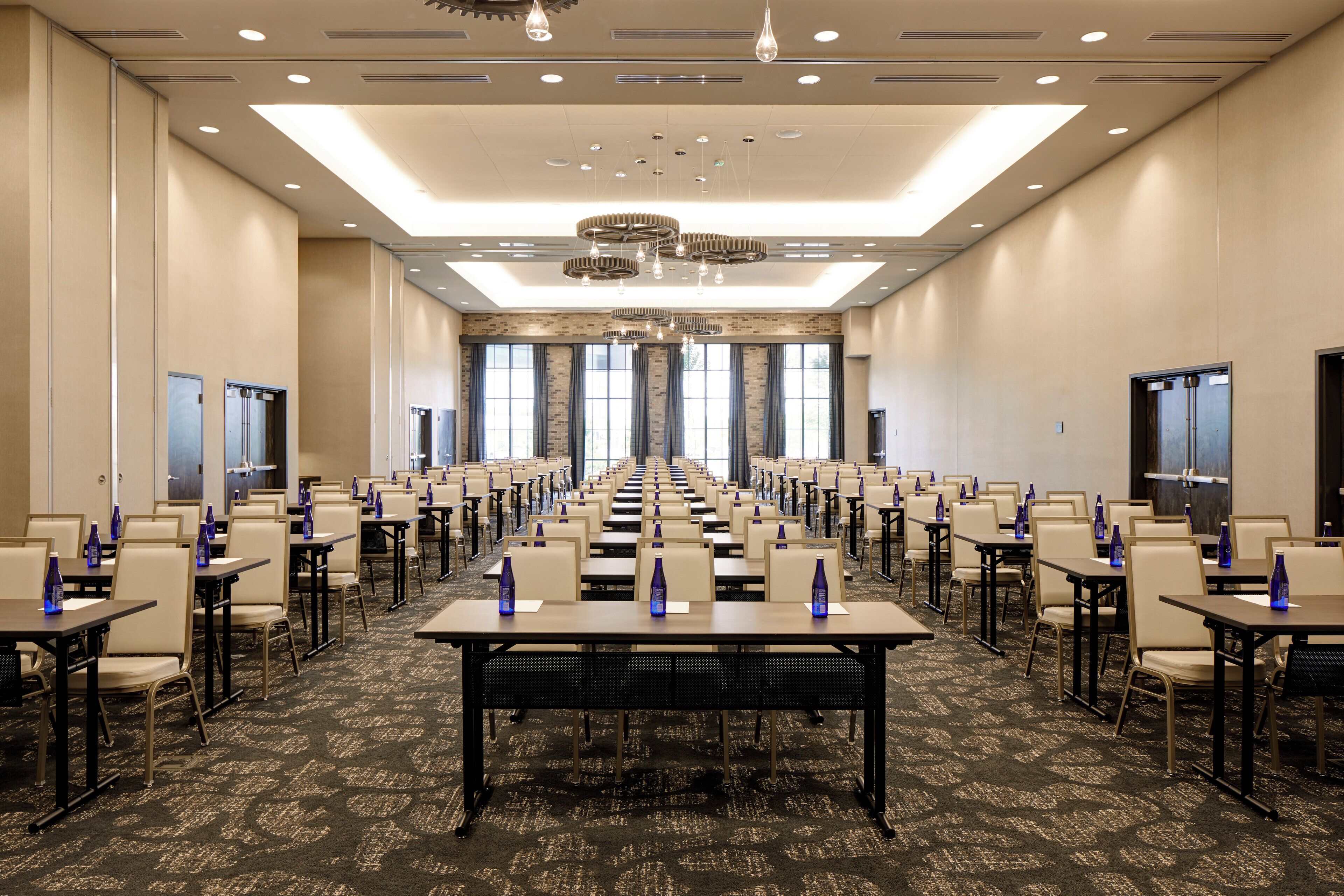 A large conference room with rows of tables and chairs, equipped with nameplates and water bottles.