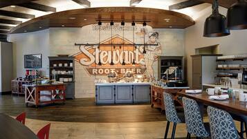 Un restaurante con un letrero grande que dice 'Stewart's Root Beer' y una zona de bar con taburetes.