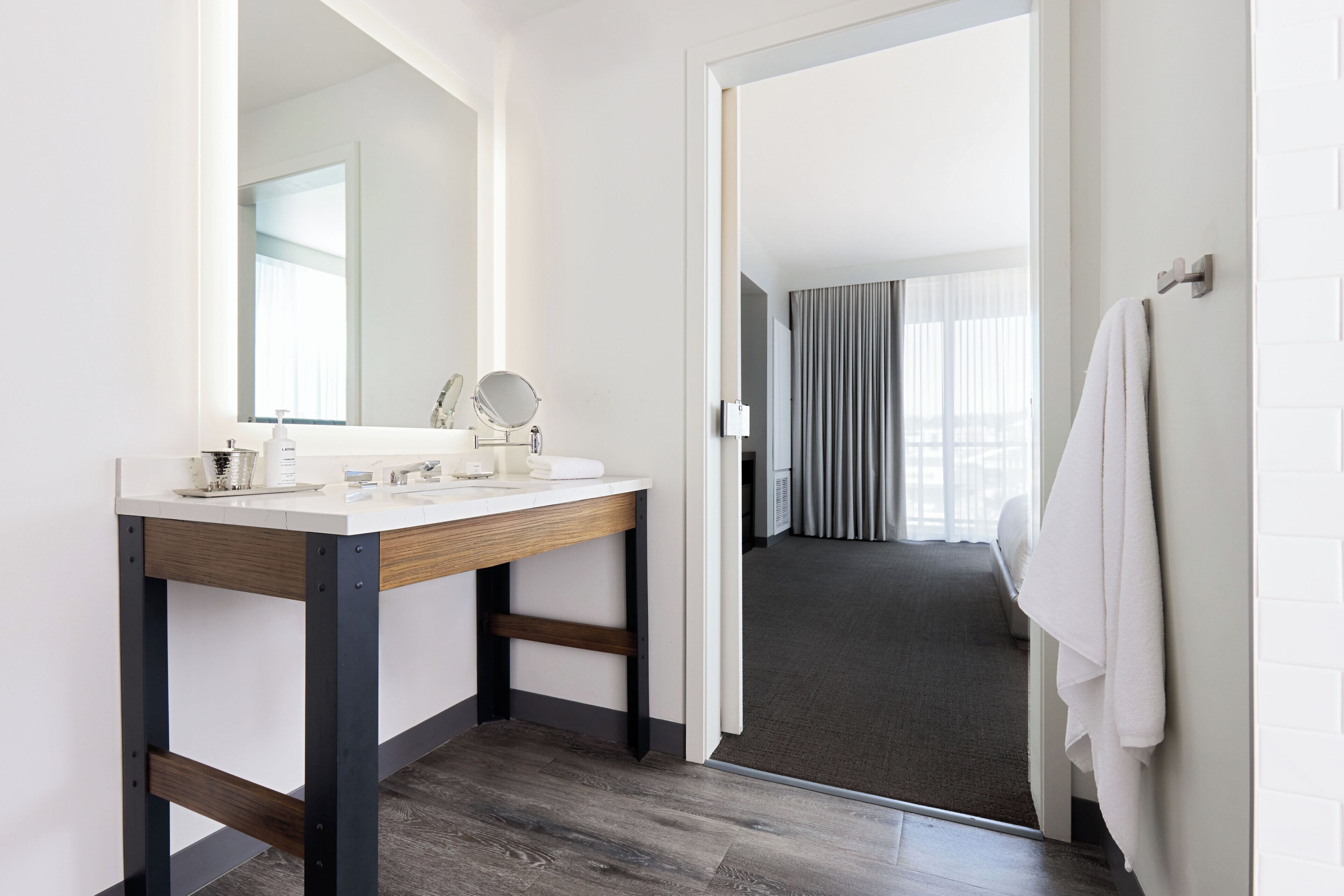 A modern bathroom with a wooden vanity, a large mirror, and a towel rack.