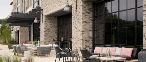 An outdoor seating area with wicker furniture and a brick building facade.