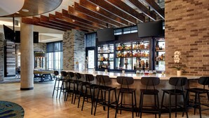 Un espace bar moderne avec un long comptoir, de nombreux tabourets et un mur en briques.