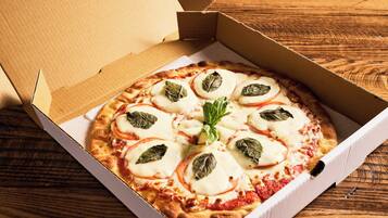 A pizza in a cardboard box on a wooden surface.