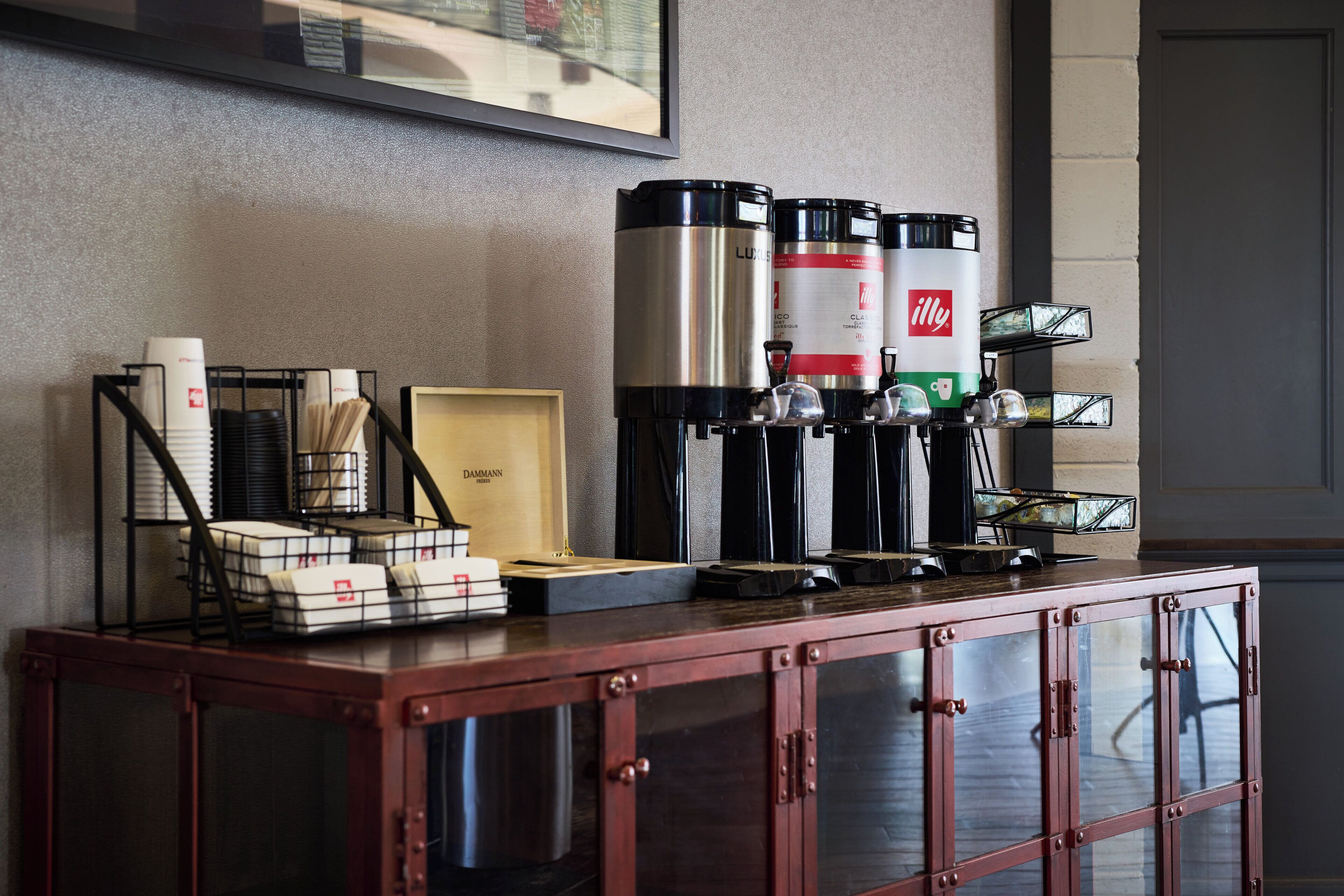 A coffee station with two coffee makers, a framed picture, and a wooden box on a cabinet.