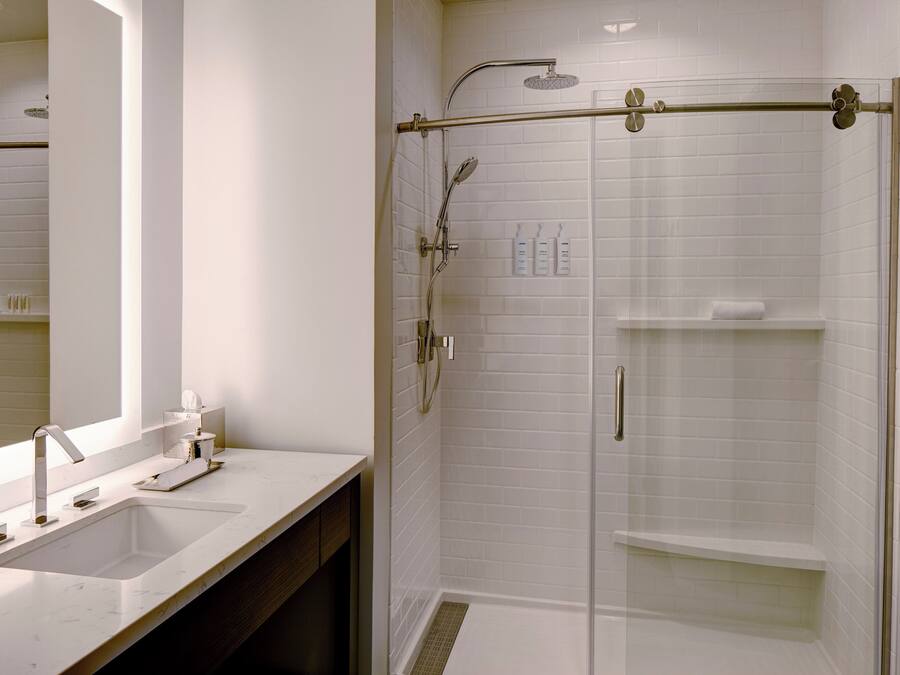 A modern bathroom with a glass-enclosed shower, a large mirror, and a white sink.