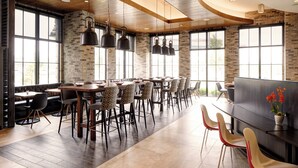 Un espace de restauration moderne avec des murs en briques, de grandes fenêtres et différents types de sièges, notamment des tables et des chaises.