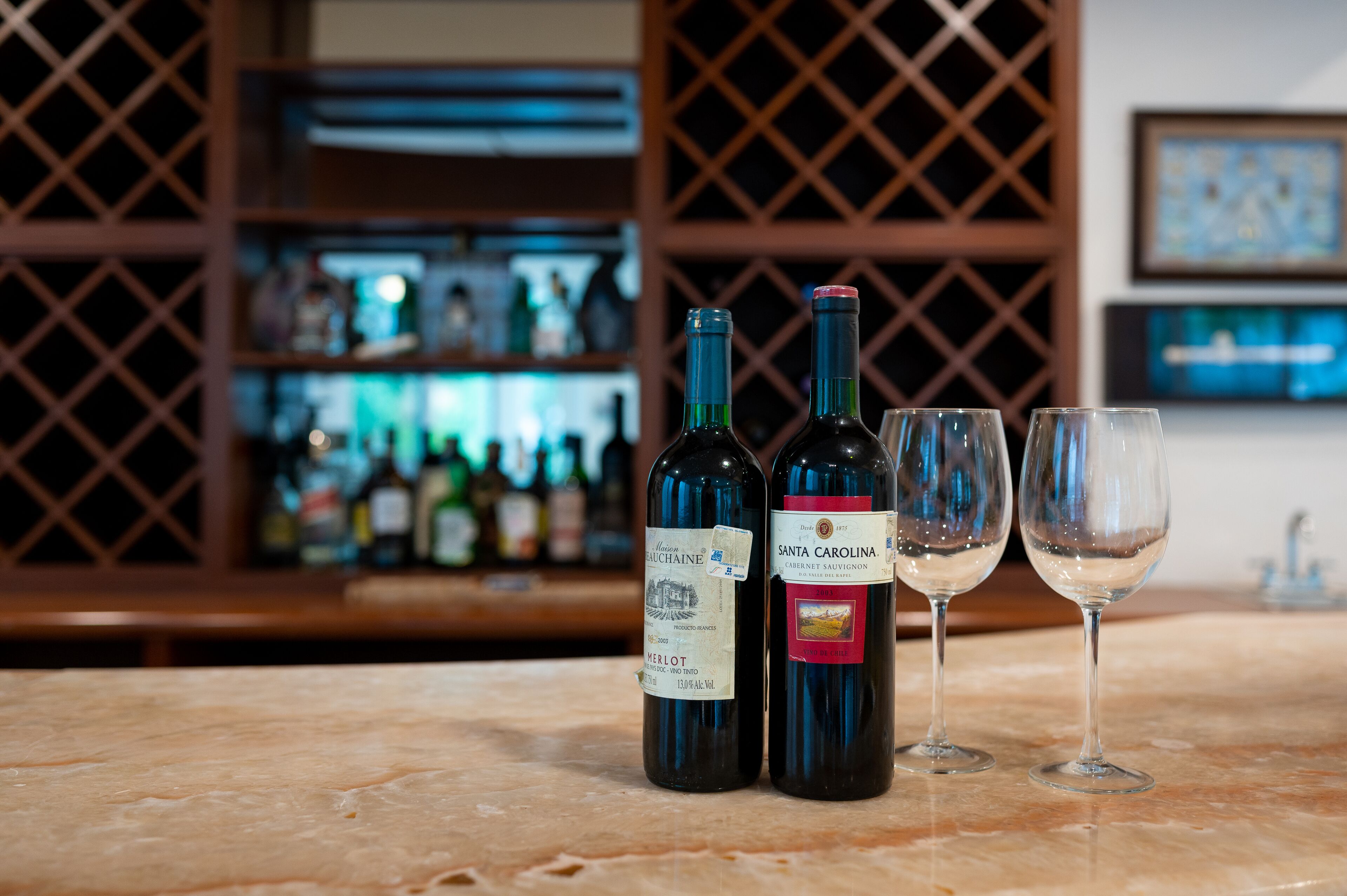 Deux bouteilles de vin et deux verres à vin sont posés sur un comptoir en marbre.