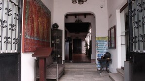 A hallway with a black gate, a wooden bench, and a colorful tapestry on the wall. - Hotel Casa las Mercedes (Oaxaca)